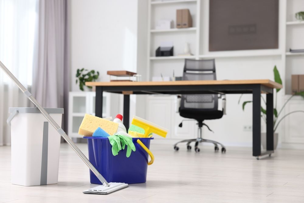 Cleaning supplies, including a mop and bucket, in an office setting.