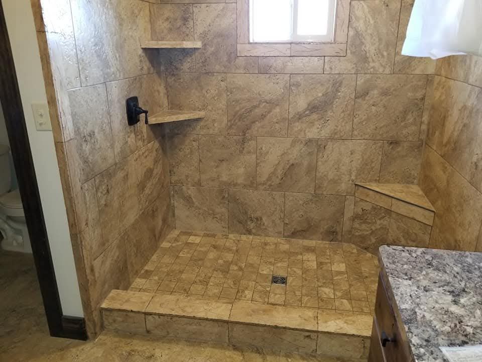 Shower with light brown tile, built-in shelves, and a small window.