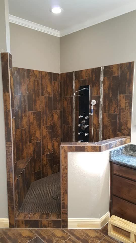 A walk-in shower with brown tiled walls and a built-in bench.