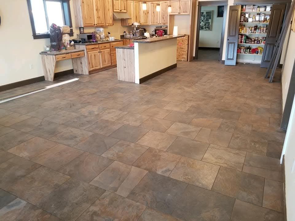 Hands laying a dark tile on mortar for flooring.