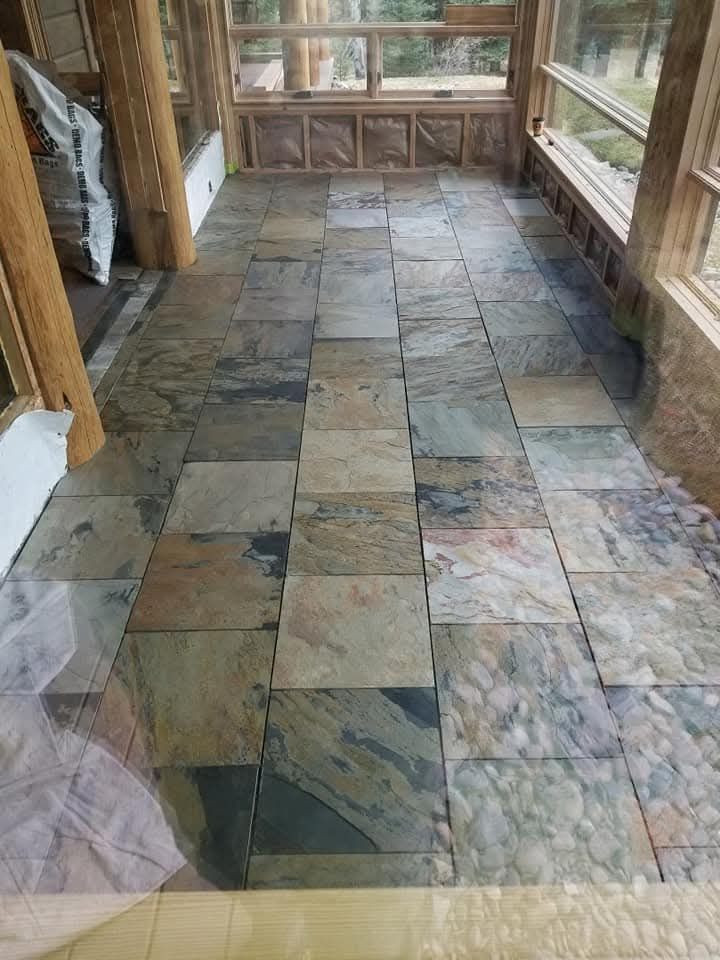 Dining room with wooden table, chairs, hardwood floors, fireplace, and large windows with a scenic view.