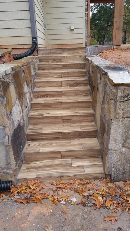 Person installing light wood-look flooring on a blue surface; close up of hands and floorboards.