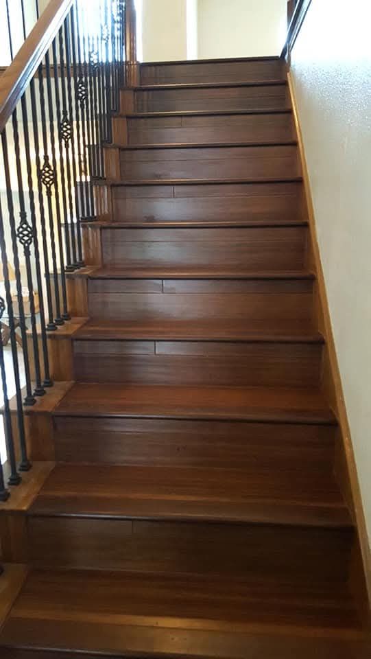 Person wearing white gloves installing laminate flooring, with measuring tape nearby.