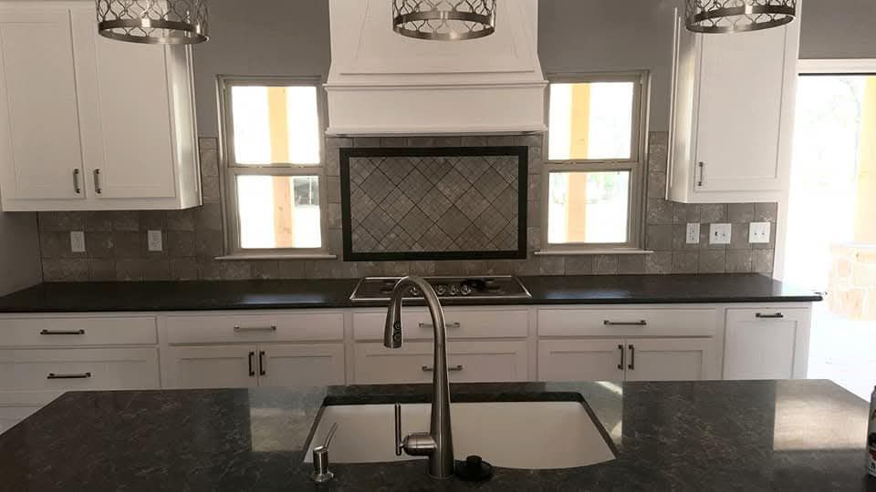 Person installing wood flooring, with tools, on a green underlayment.