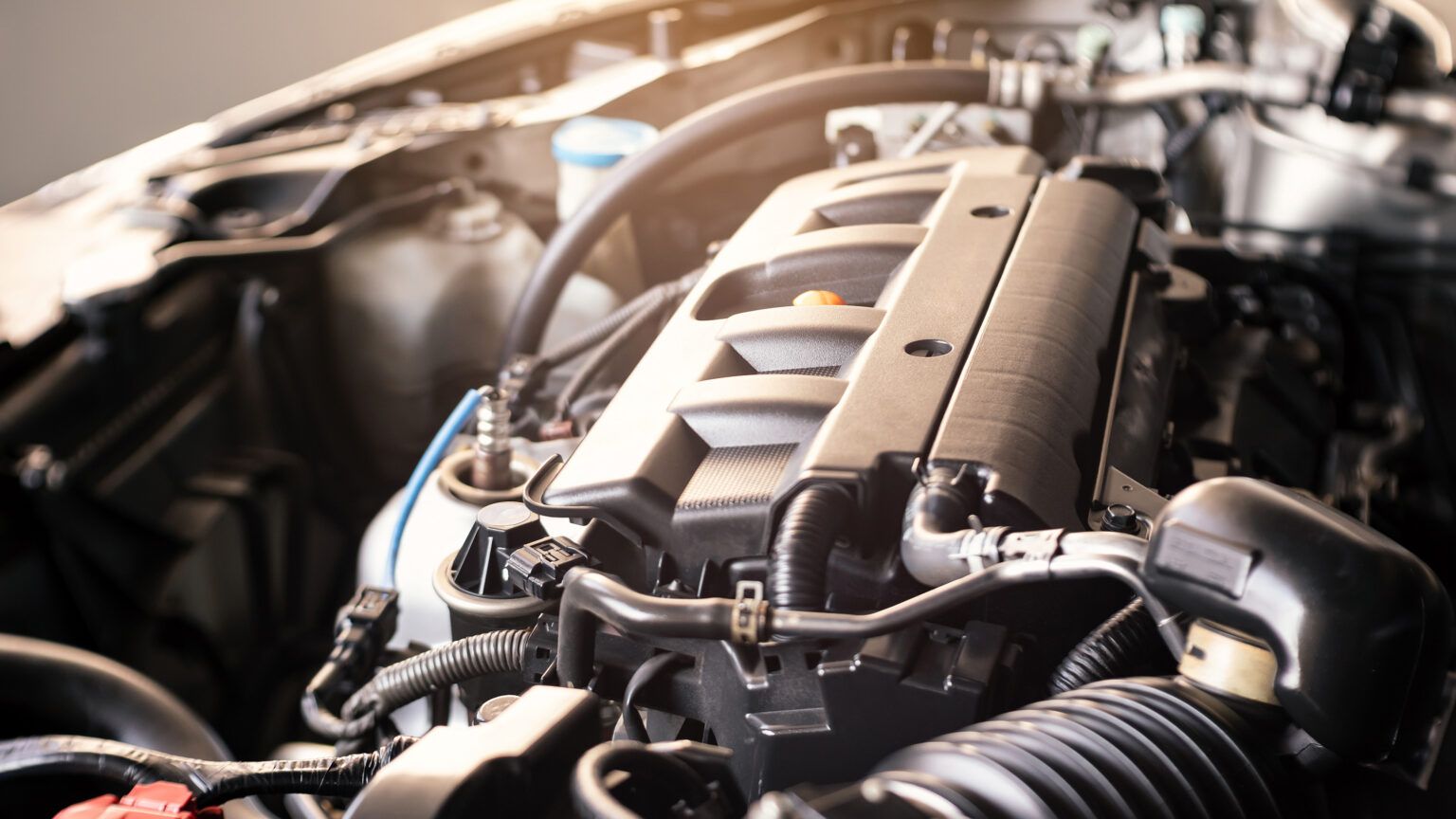 Close-up of a car engine bay with a black intake hose and metallic engine components.