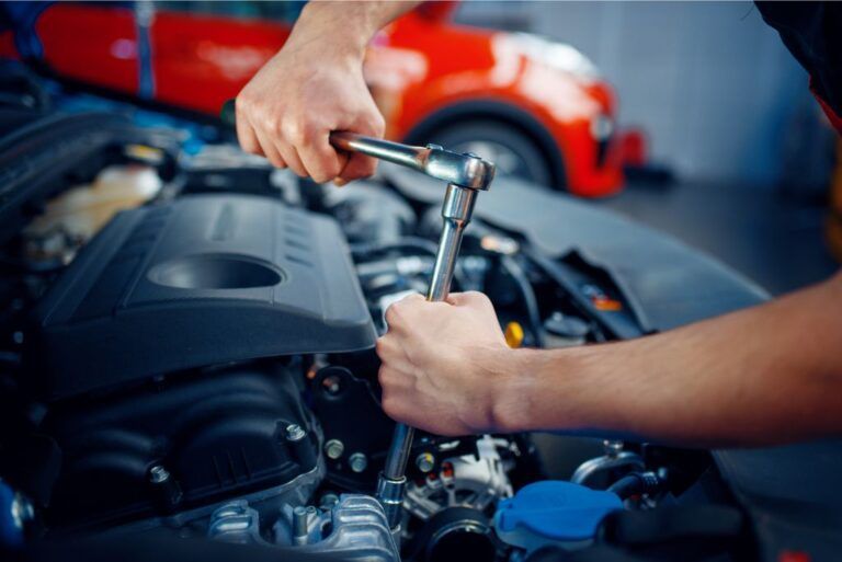 Hands using a socket wrench to work on a car engine in a garage