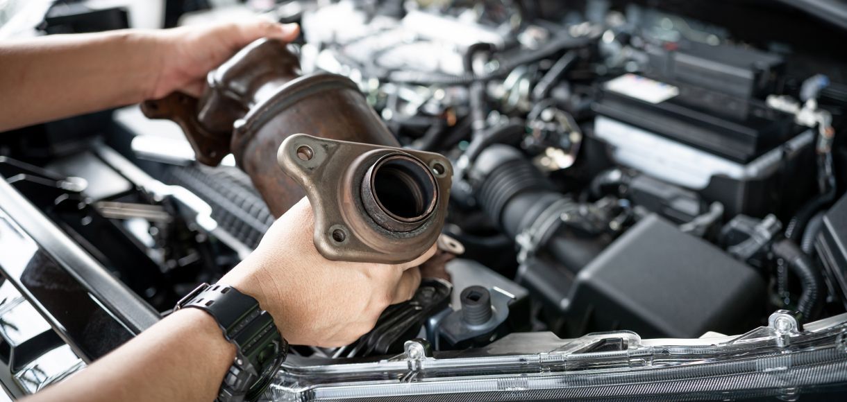 Mechanic holding a turbocharger over an open car engine in a repair shop
