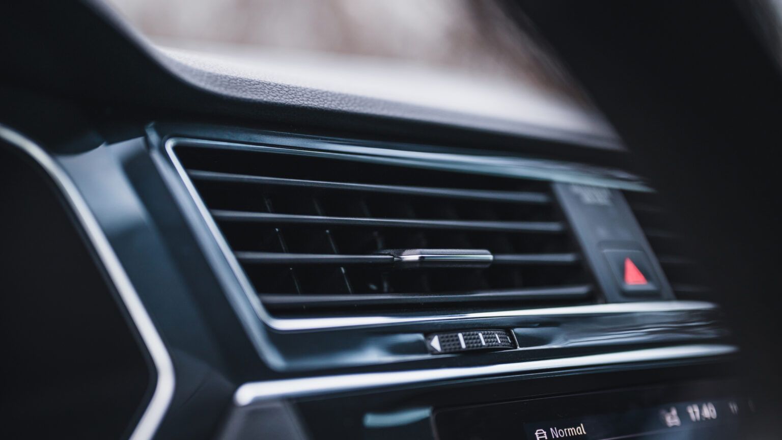 Close-up of a car dashboard air vent with a red hazard light button
