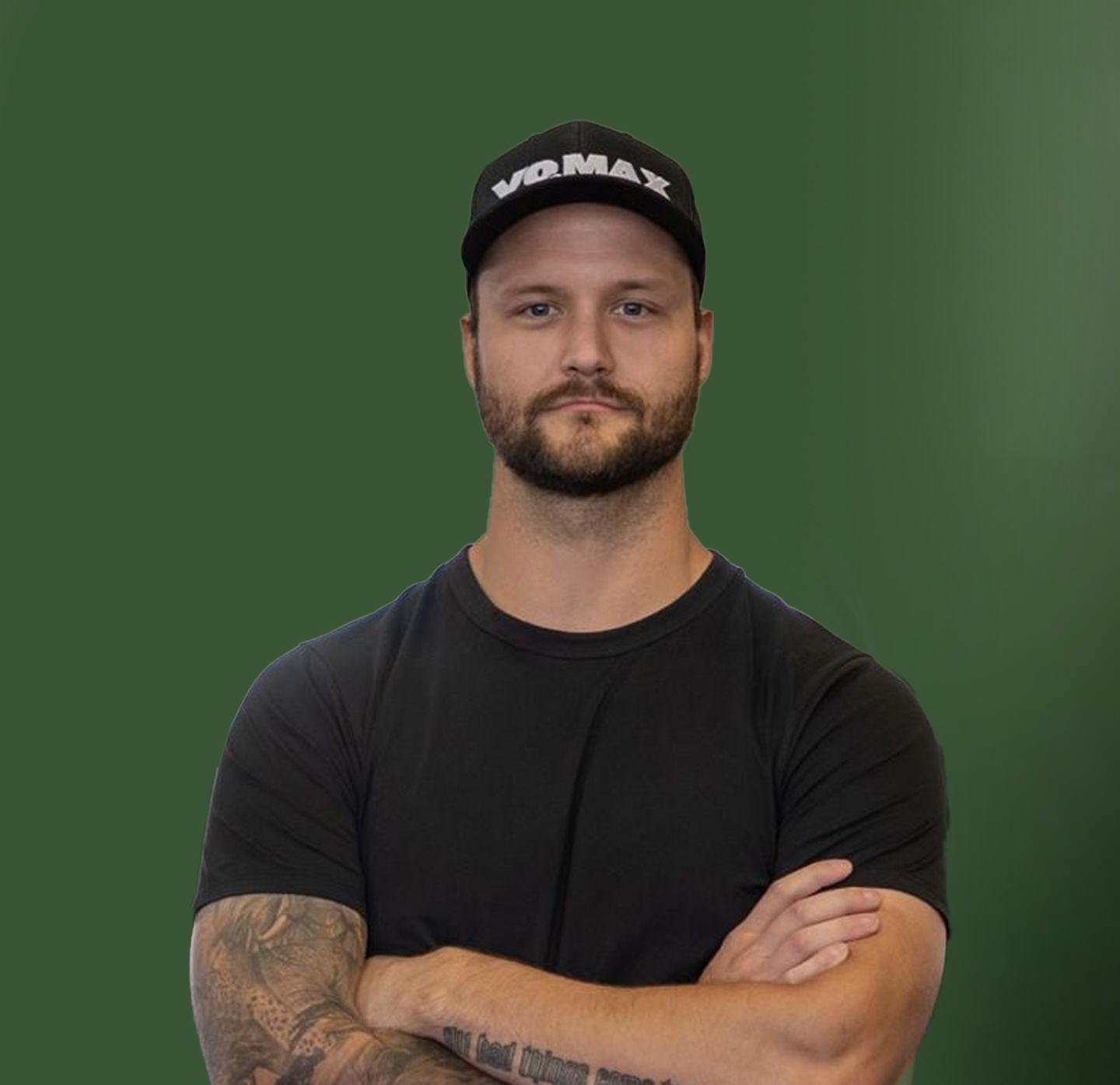 A man with a tattoo on his arm is wearing a vomax hat