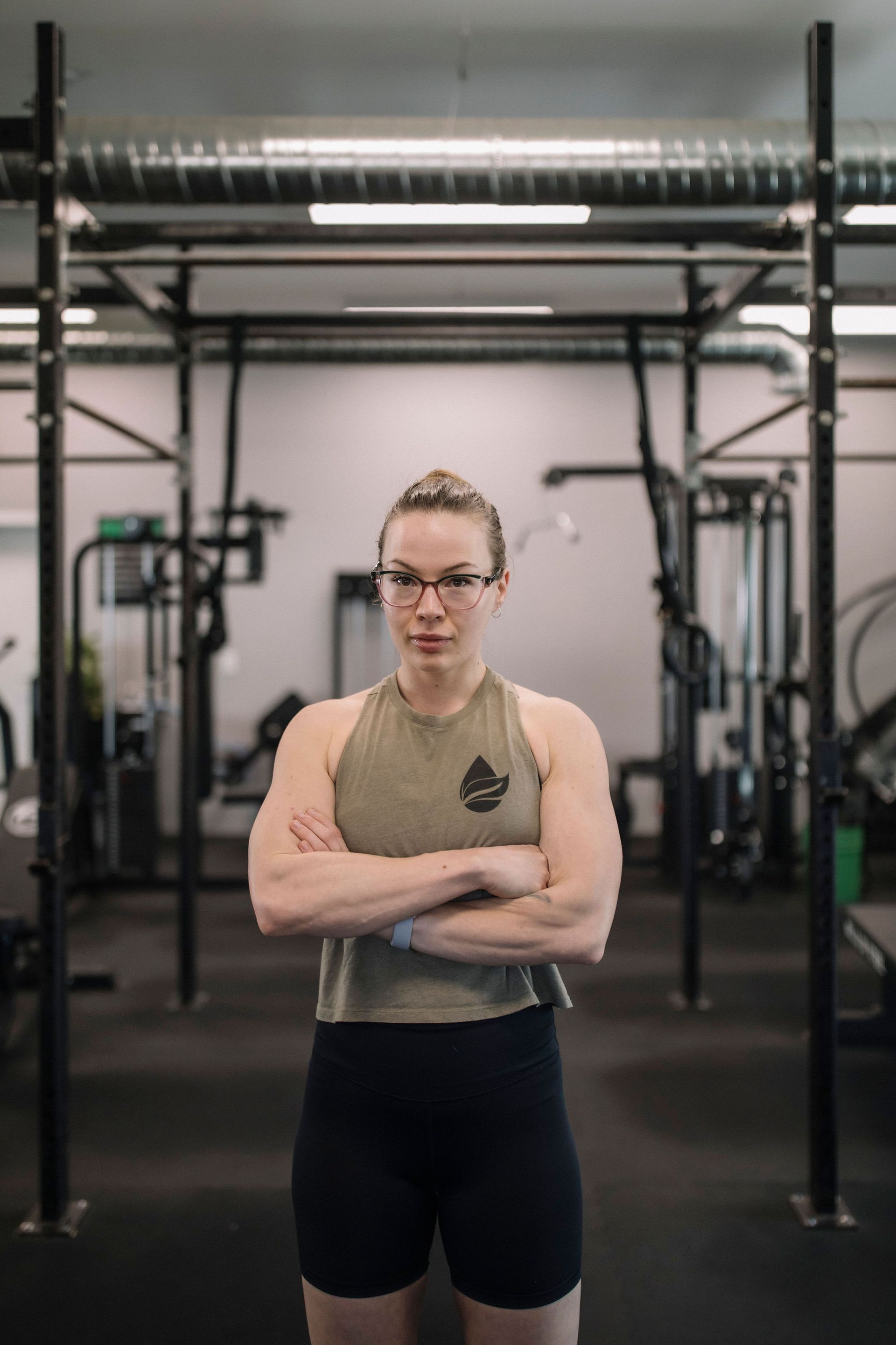 A woman wearing glasses and a black tank top with the word sweat on it.
