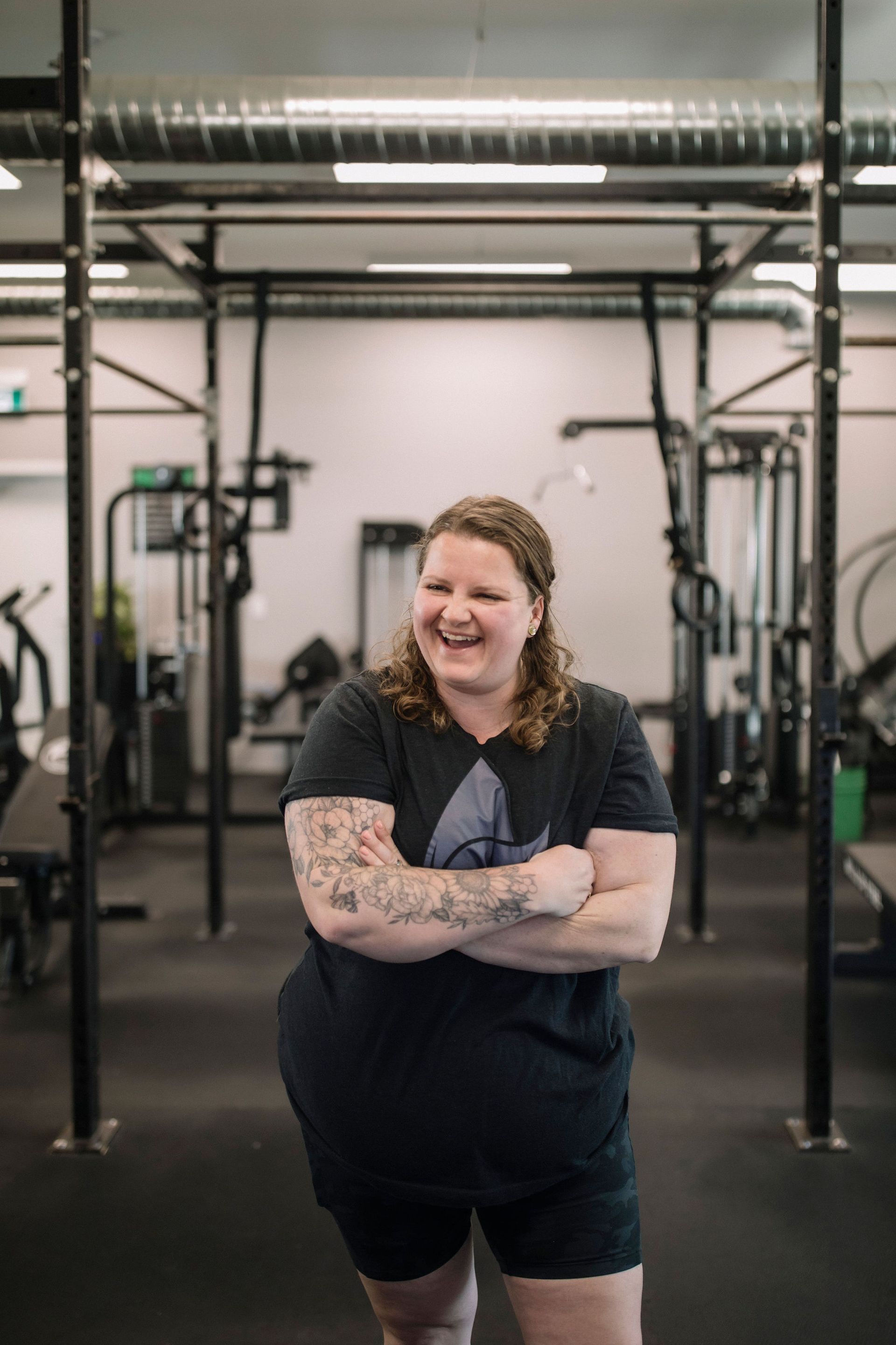 A woman in a black tank top is holding a black ball in a gym