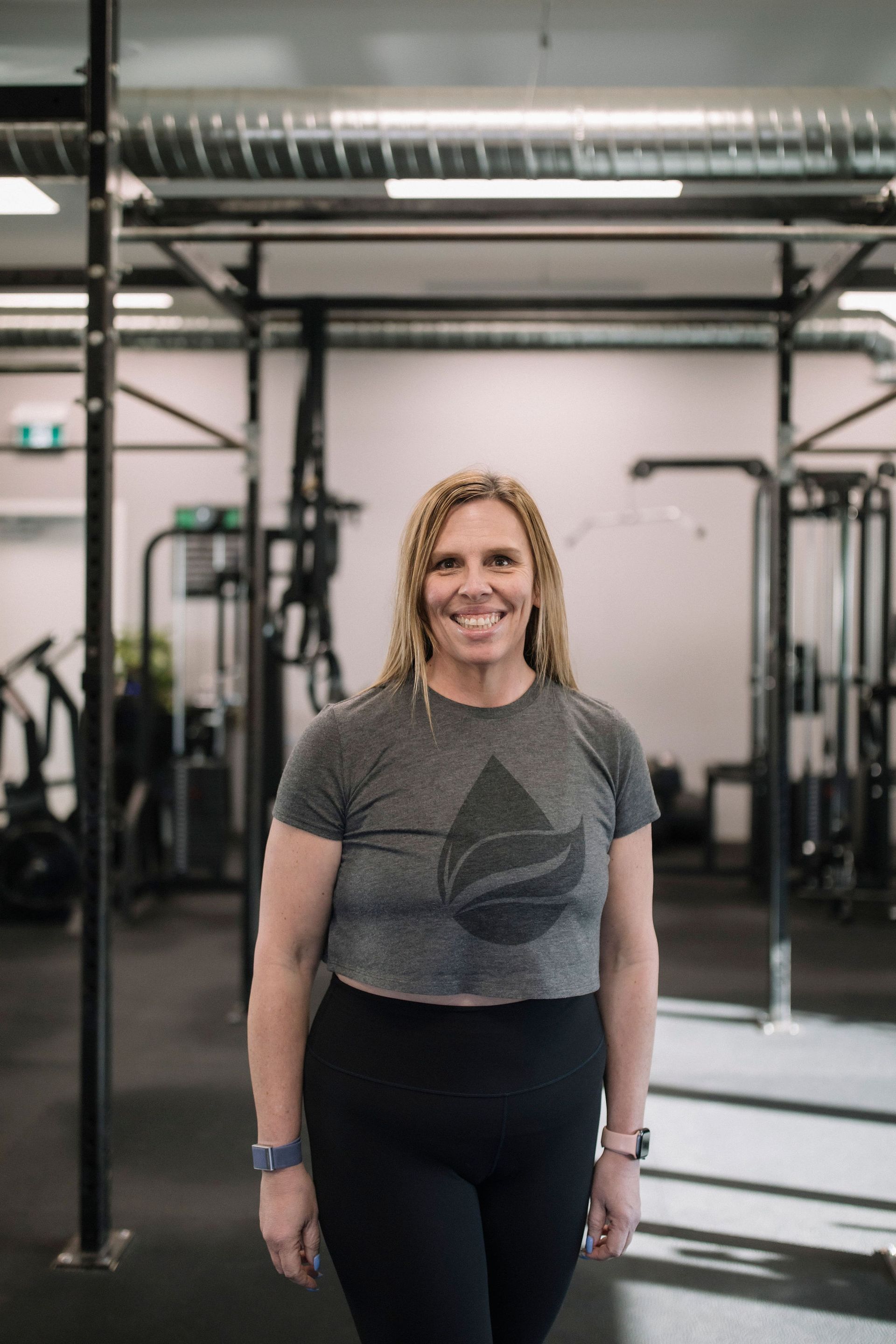A woman in a grey tank top is smiling for the camera.