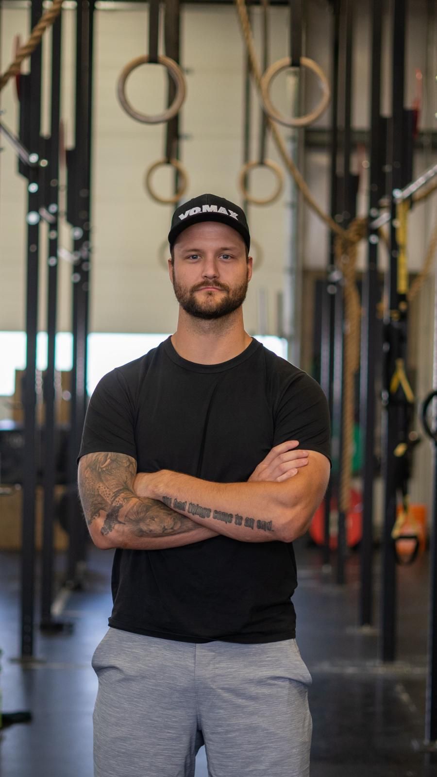 A man with a tattoo on his arm is wearing a vomax hat