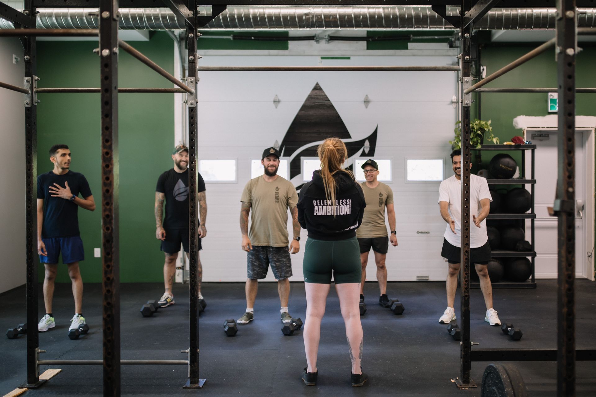 A group of people are standing in a gym with a woman standing in front of them.