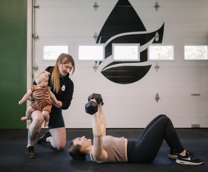 A baby is sitting on the floor holding a barbell