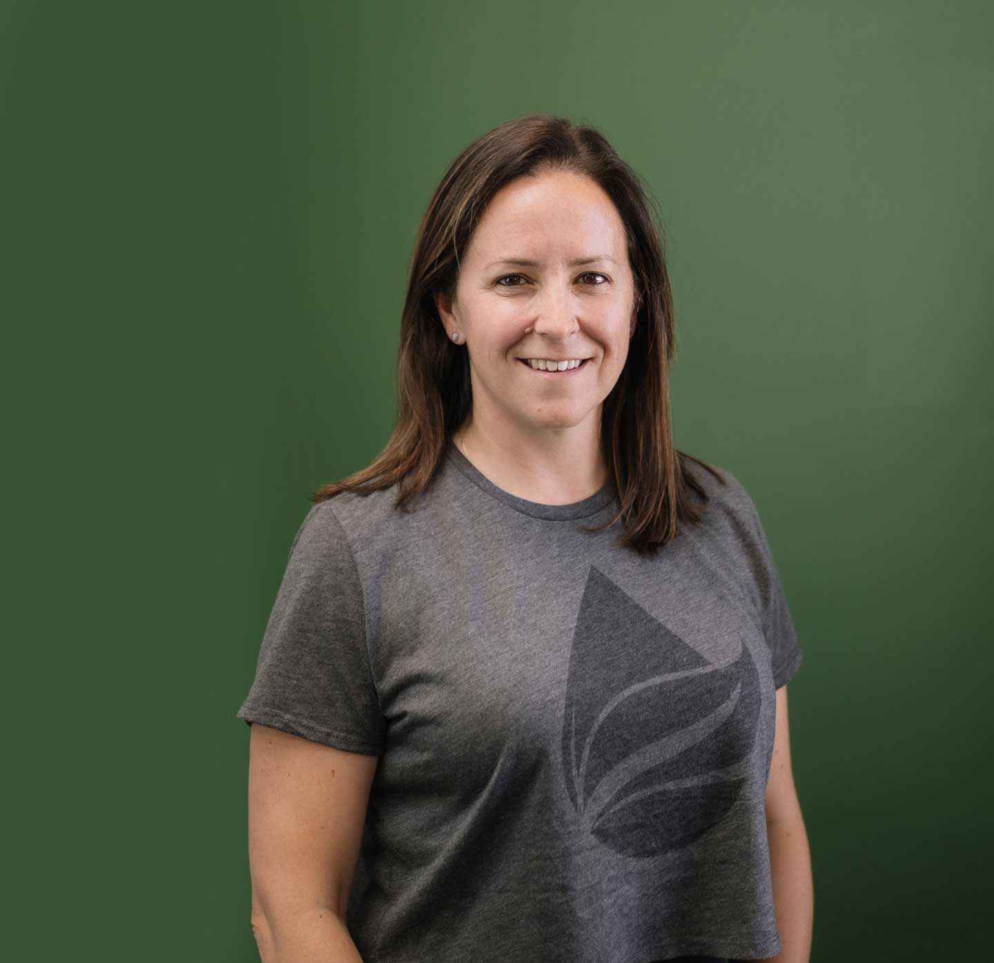A woman in a grey tank top is smiling for the camera.