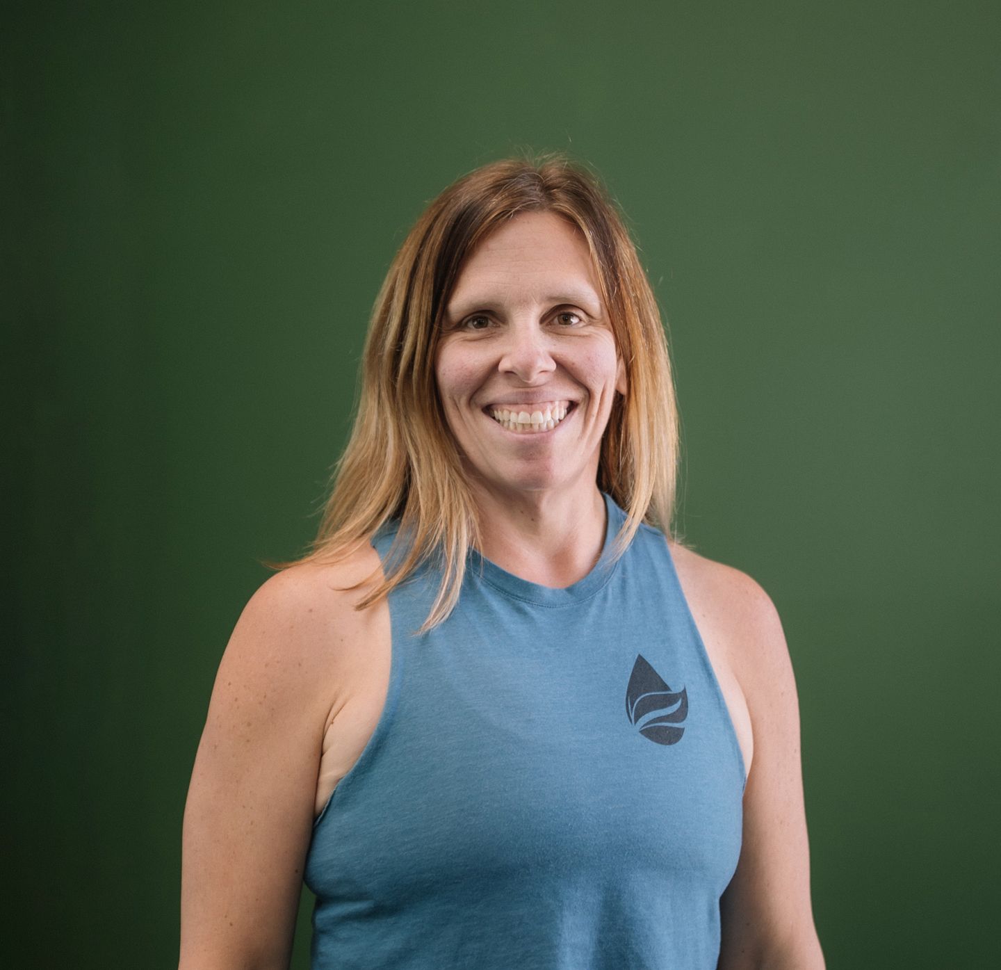 A woman in a grey tank top is smiling for the camera.
