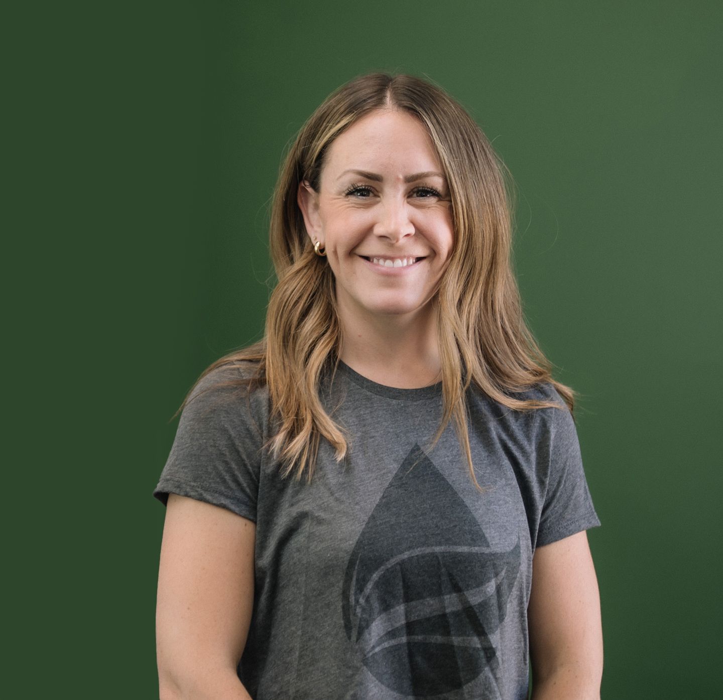 A man wearing a hat and glasses is standing with his arms crossed in a gym.