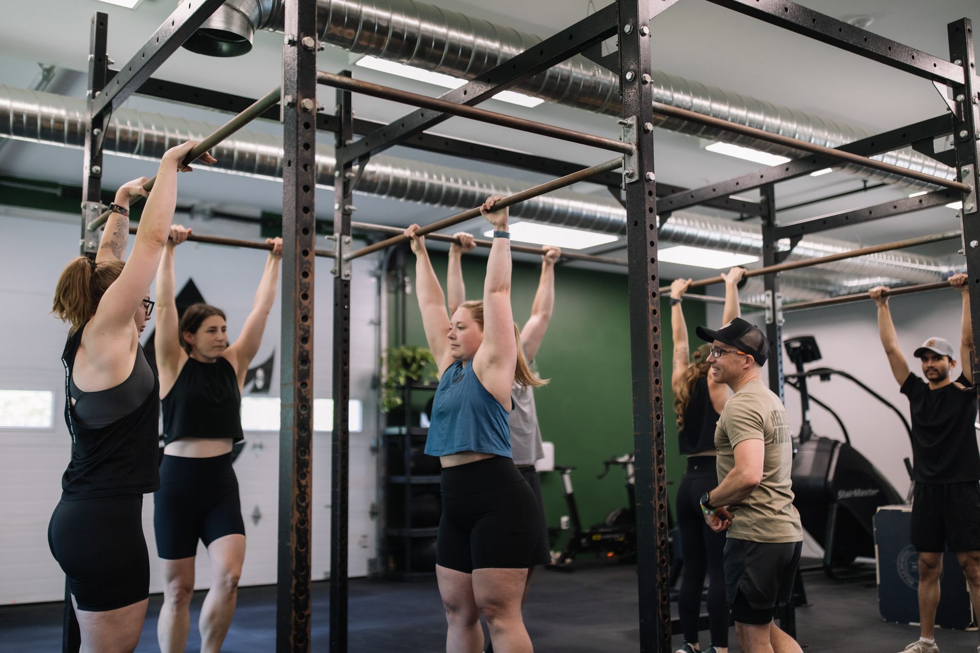 A group of people are doing pull ups in a gym.