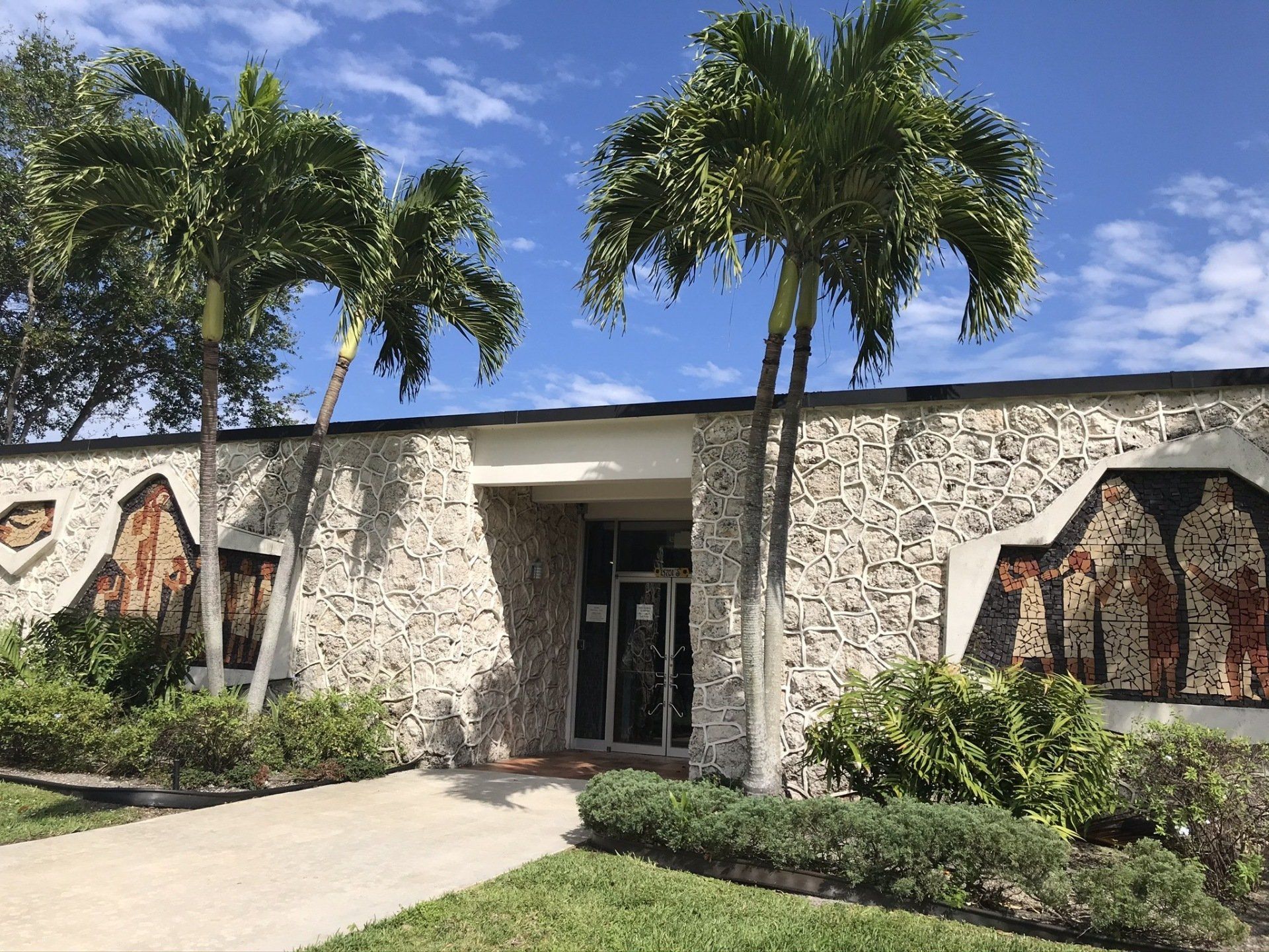 A large stone building with palm trees in front of it.