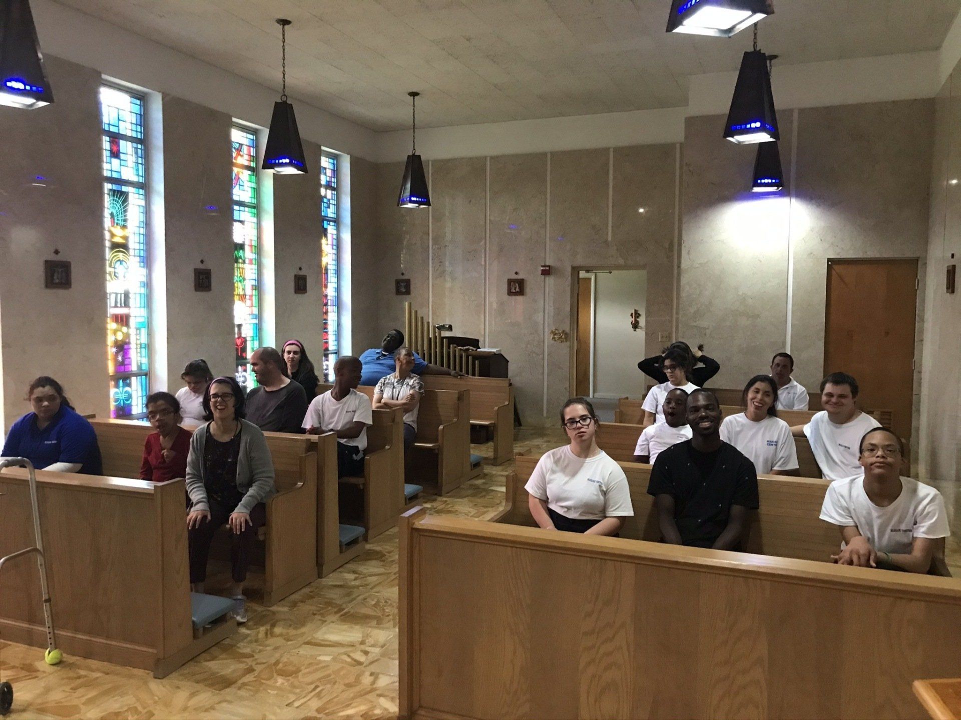 A group of people are sitting in a church with stained glass windows.