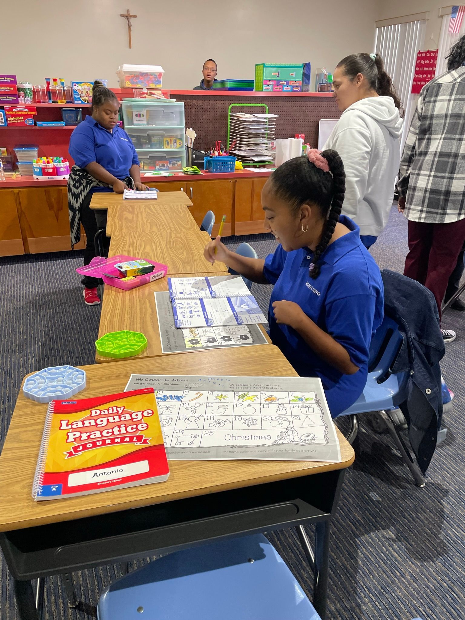 A group of children are sitting on a rug in a classroom.