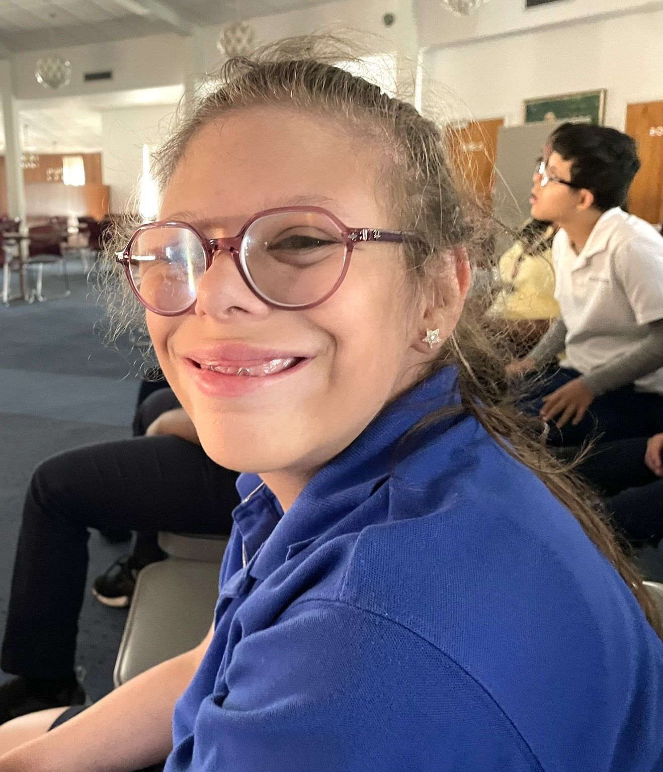 A girl wearing glasses and a blue shirt is smiling