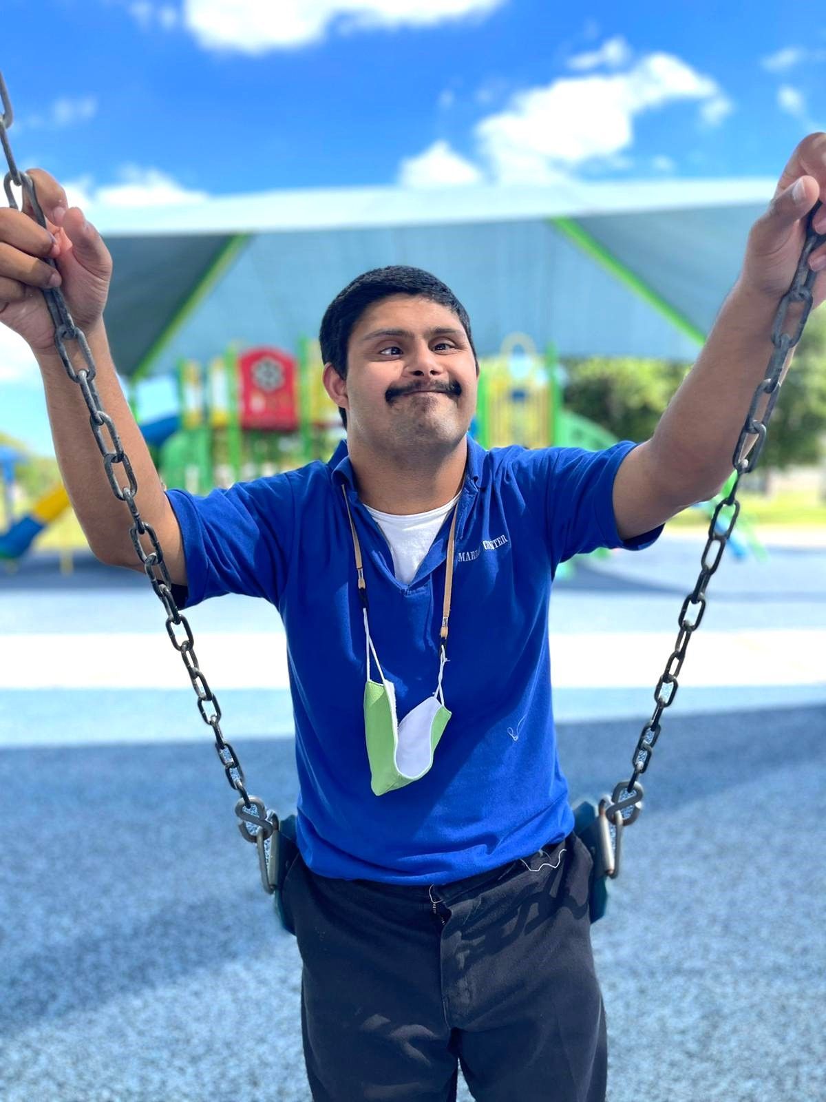 A man in a blue shirt is swinging on a swing set