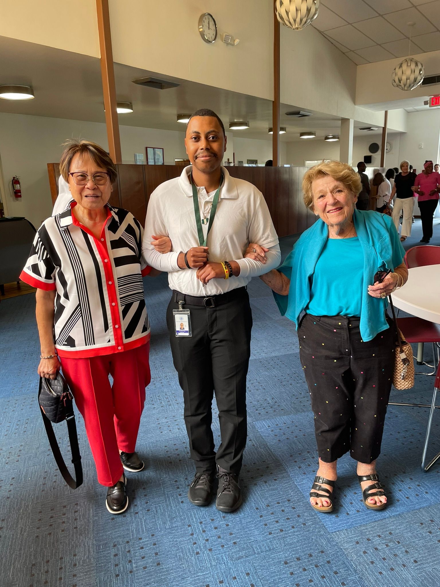 A man and two women are standing next to each other in a room.