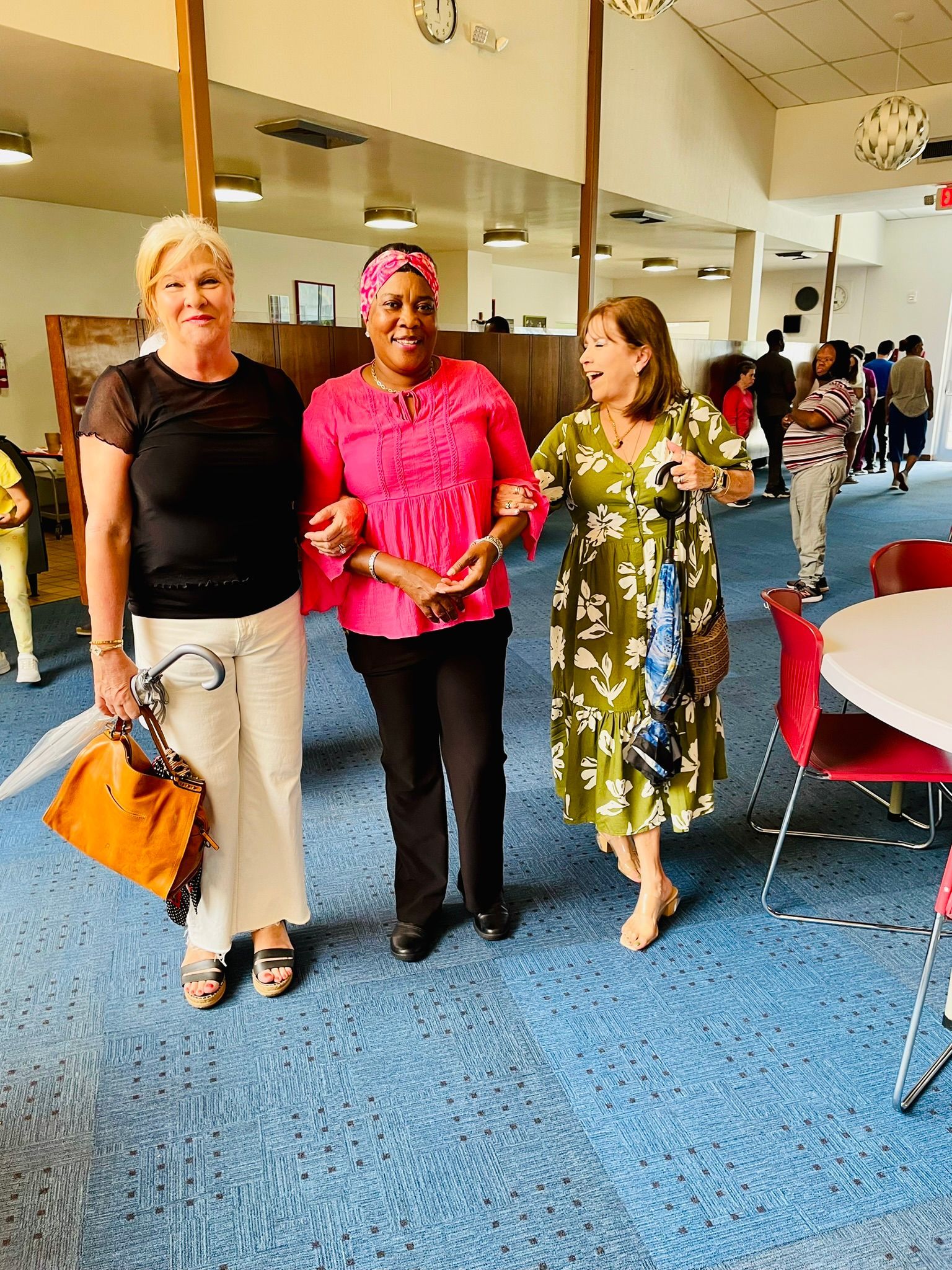 Three women are standing next to each other in a room.