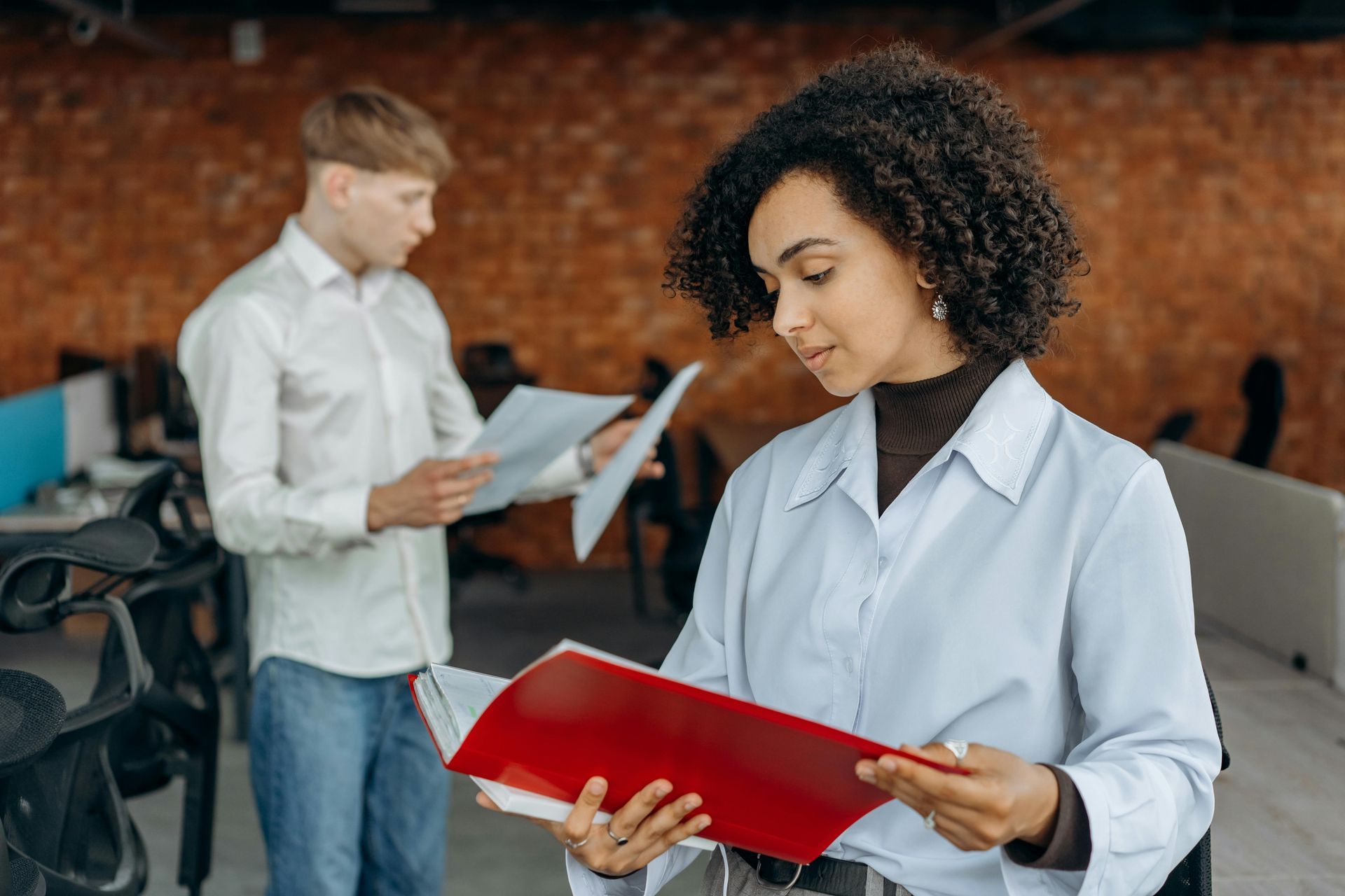 A man and a woman are looking at papers in an office.