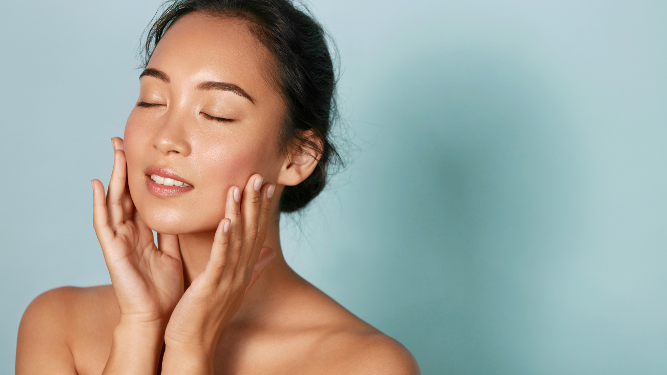 Person gently touching their face with closed eyes against a soft blue background