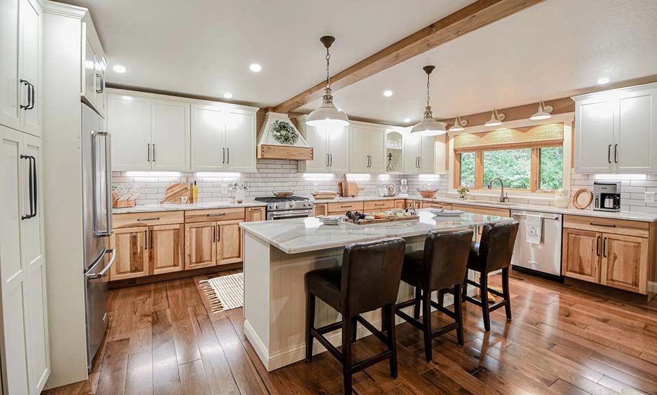 A kitchen with white cabinets and wooden floors and a large island.