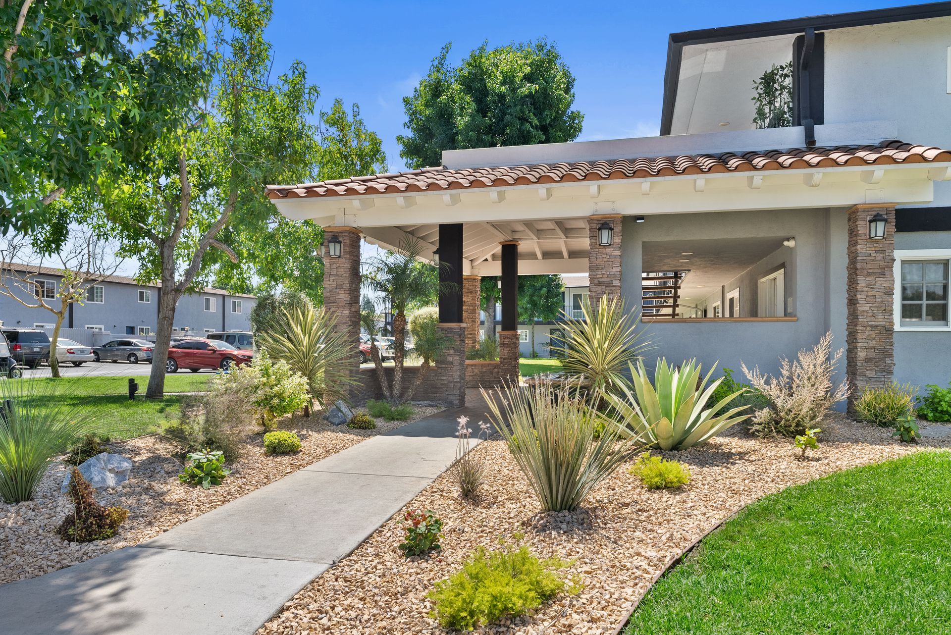 Exterior walkway with gravel and plants leading towards office building at Villa Del Sol