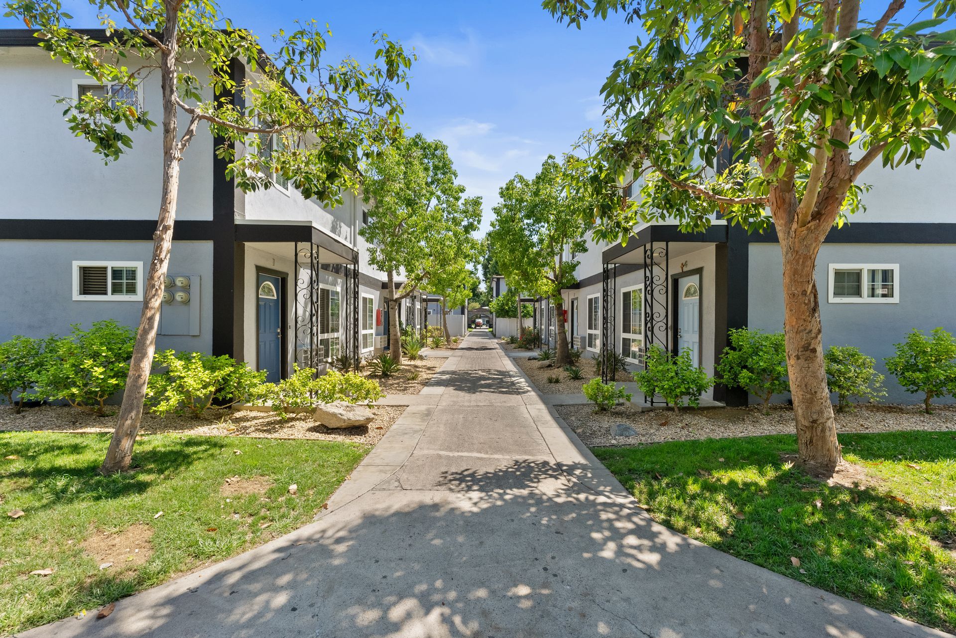 Exterior concrete walkway between two double story white buildings at Villa Del Sol