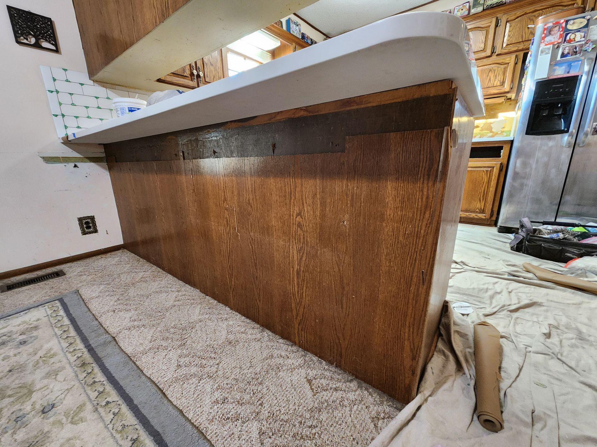 Brown wood kitchen island with white countertop in a kitchen.