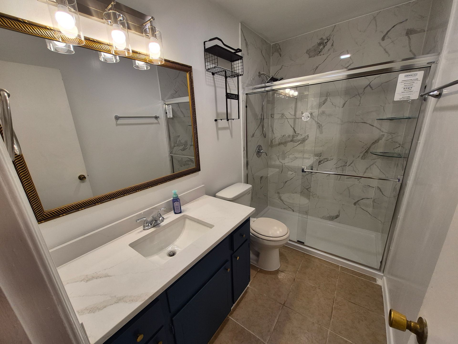 Bathroom with a blue vanity, marble countertop, and shower with glass doors.