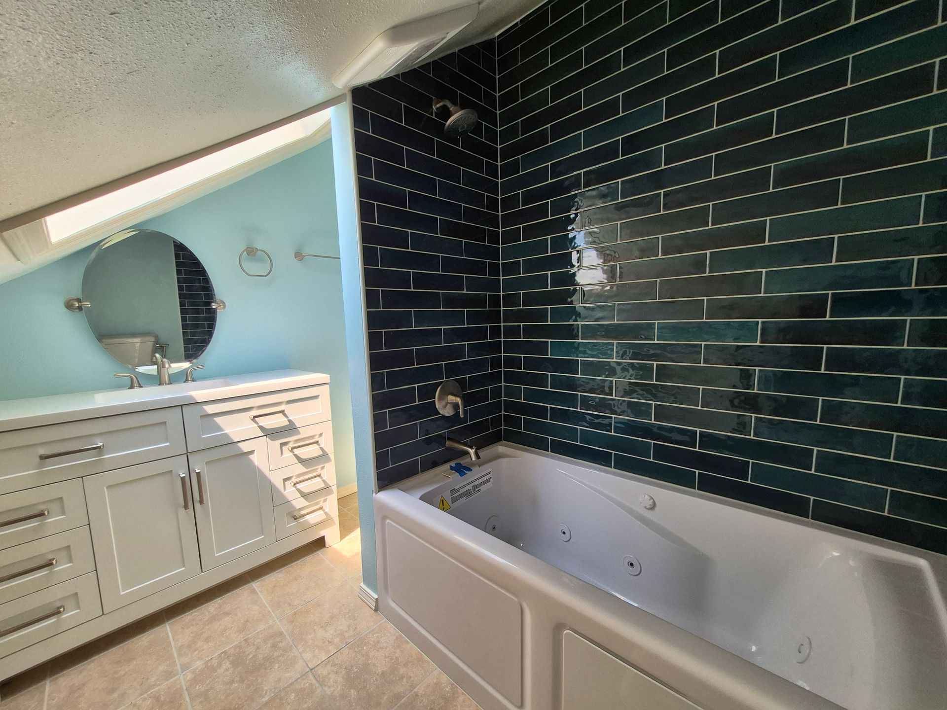 Bathroom with white vanity, blue walls, dark blue tiled shower, and a white tub.