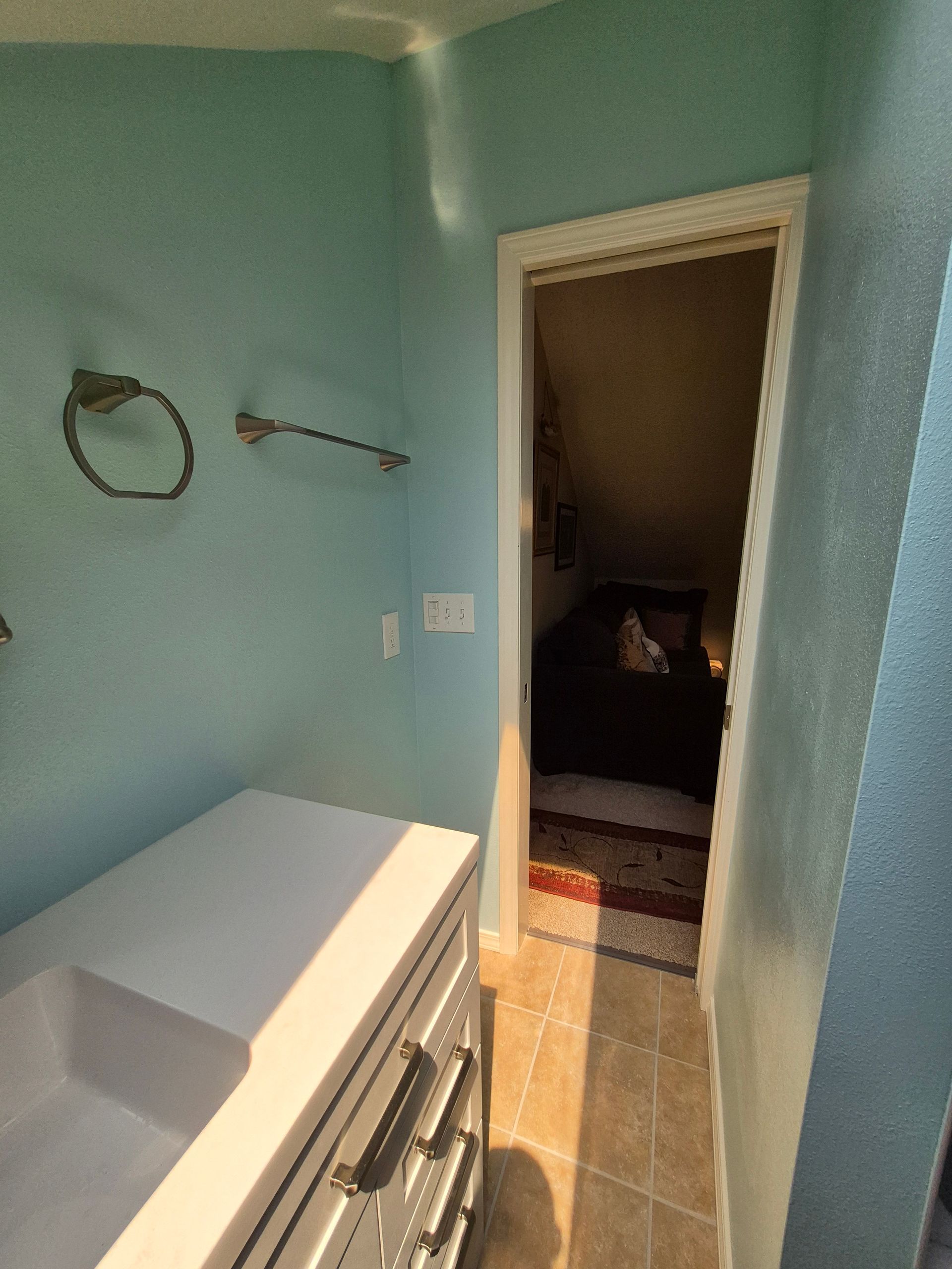 Bathroom with blue walls, white vanity, and open doorway to a bedroom.