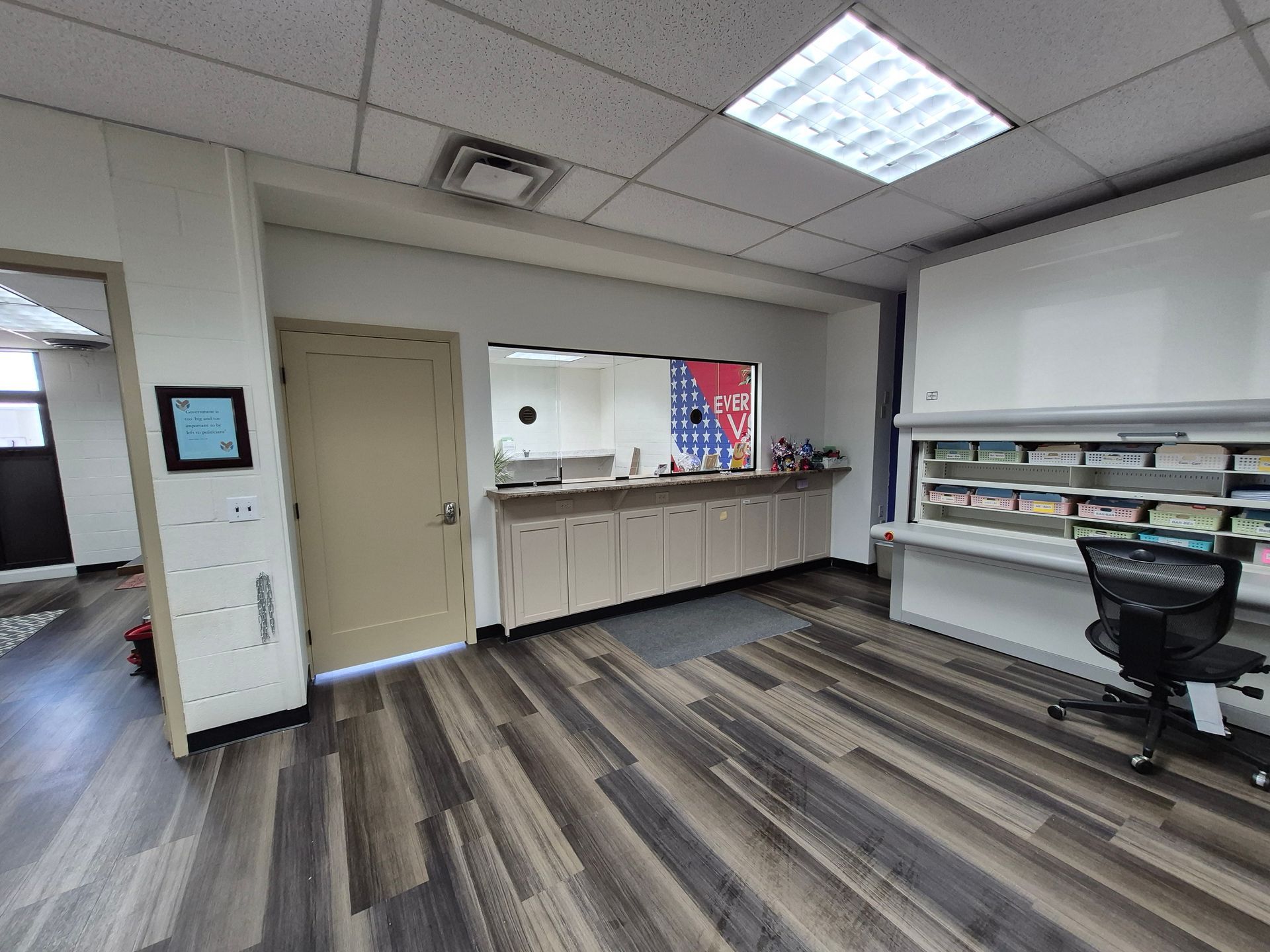 Interior office space with wood flooring, cabinets, a door, and a chair.