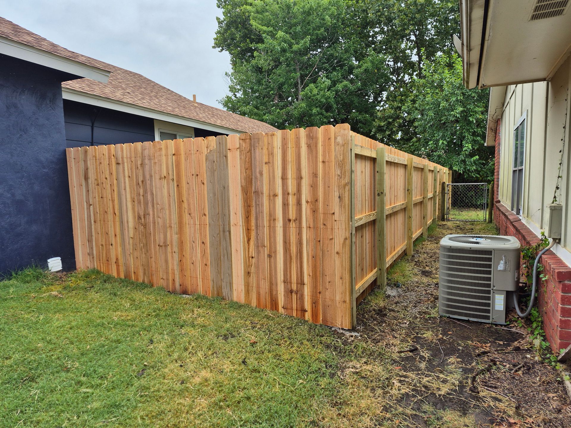 Wooden privacy fence between two houses in a grassy yard.
