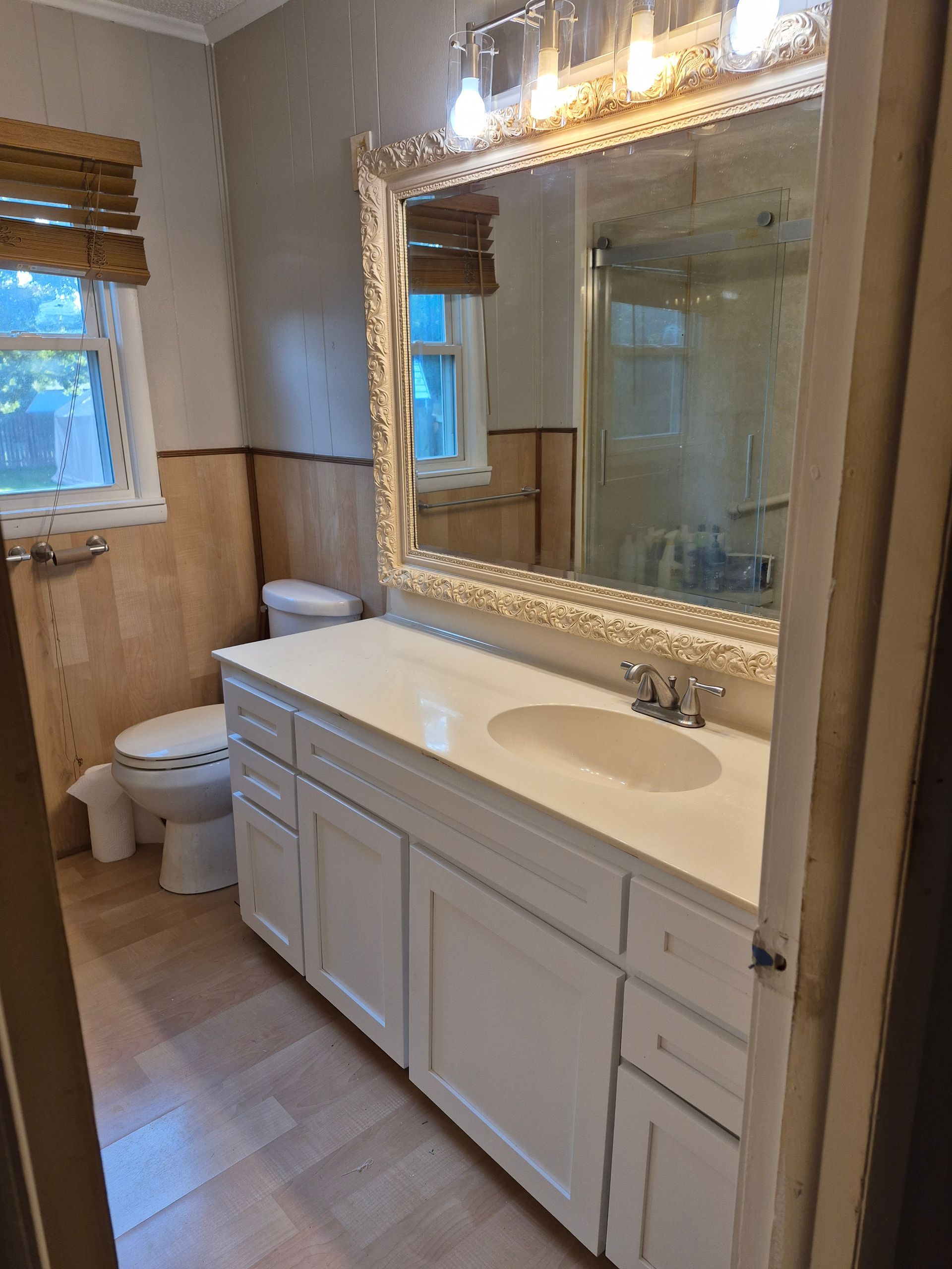 Bathroom with white vanity, large mirror, toilet, and shower visible.
