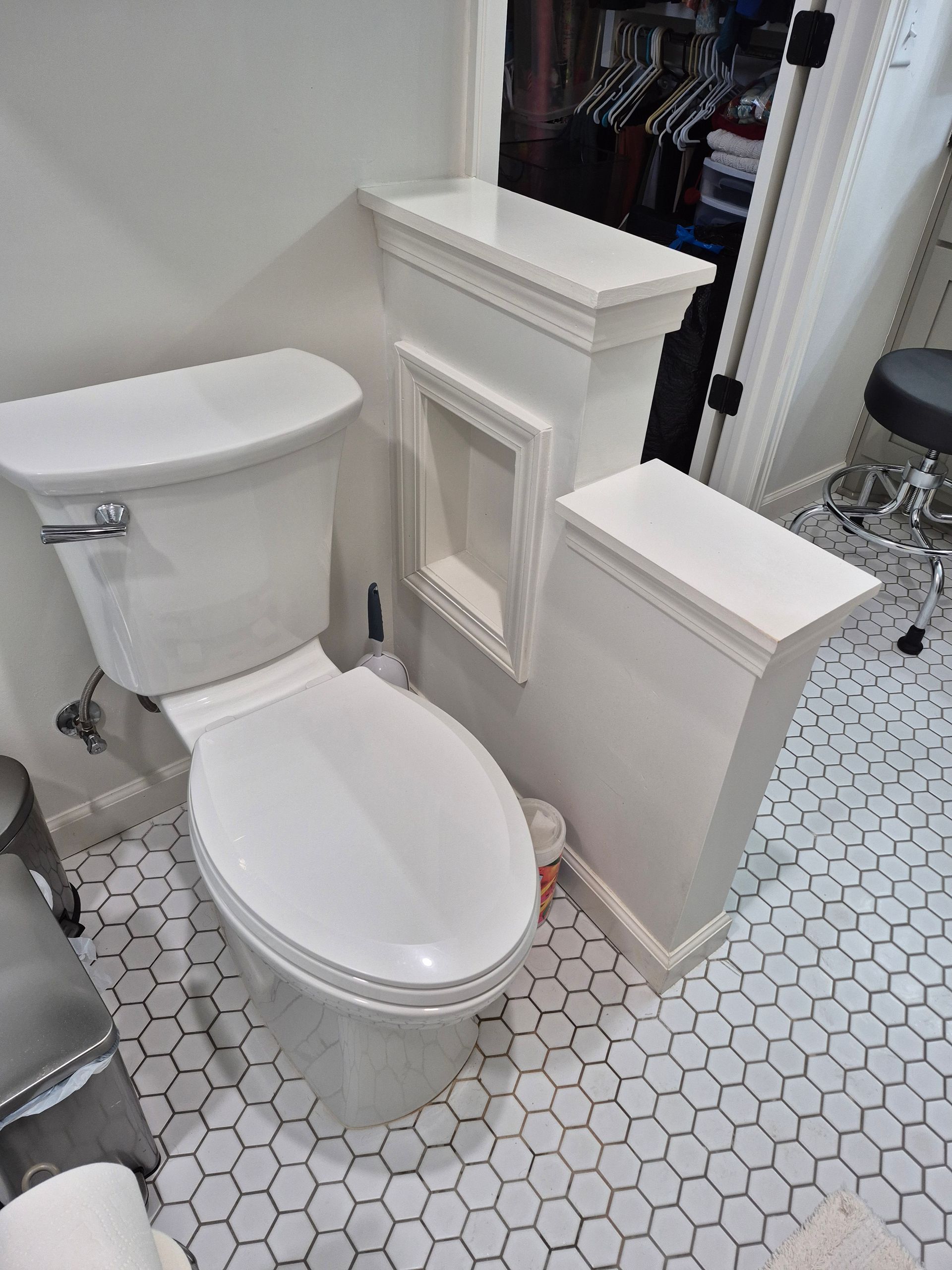 Toilet in a white bathroom, with decorative white storage units.