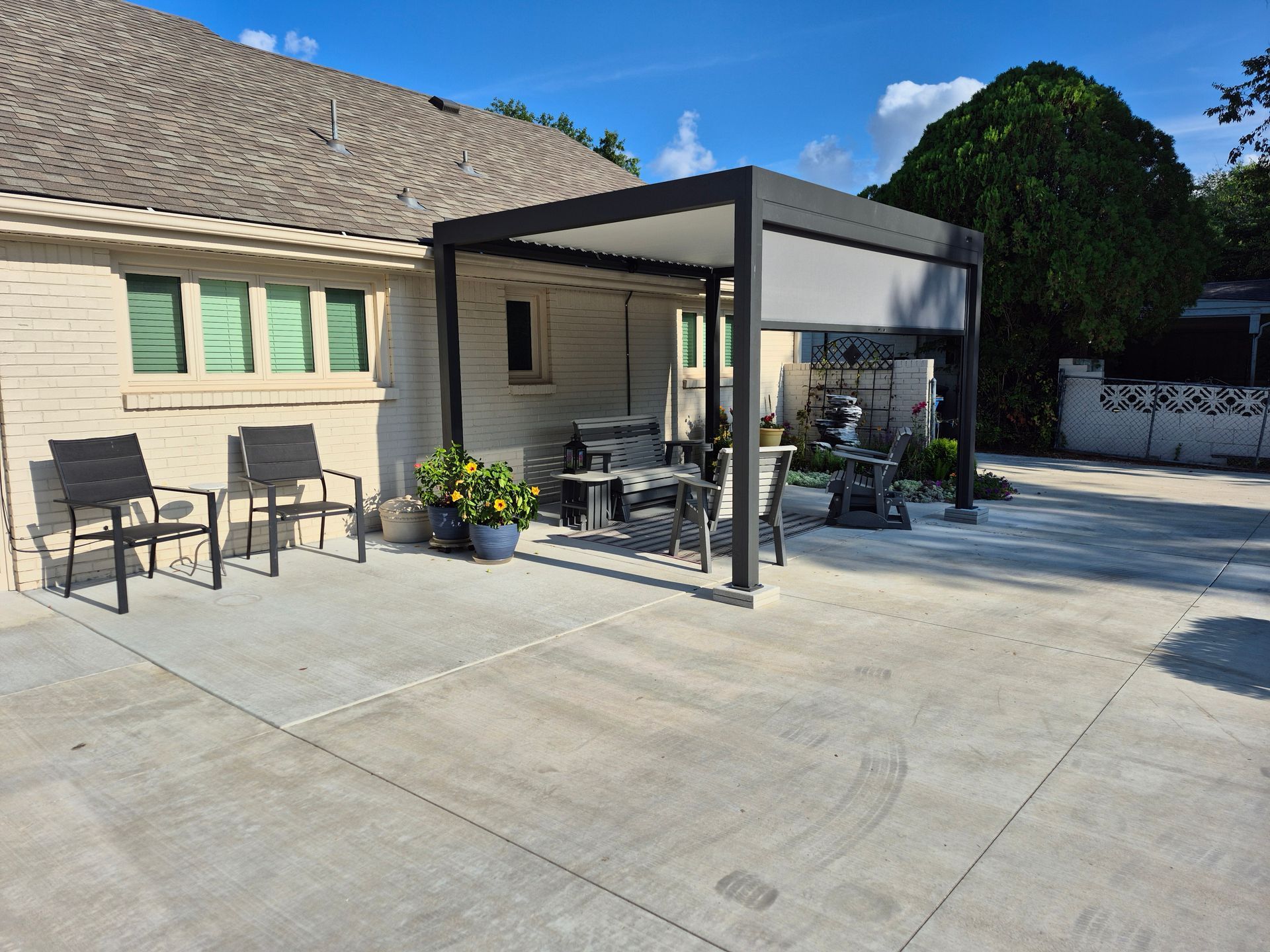 Patio with pergola, furniture, and house. Concrete patio. Sunny day.