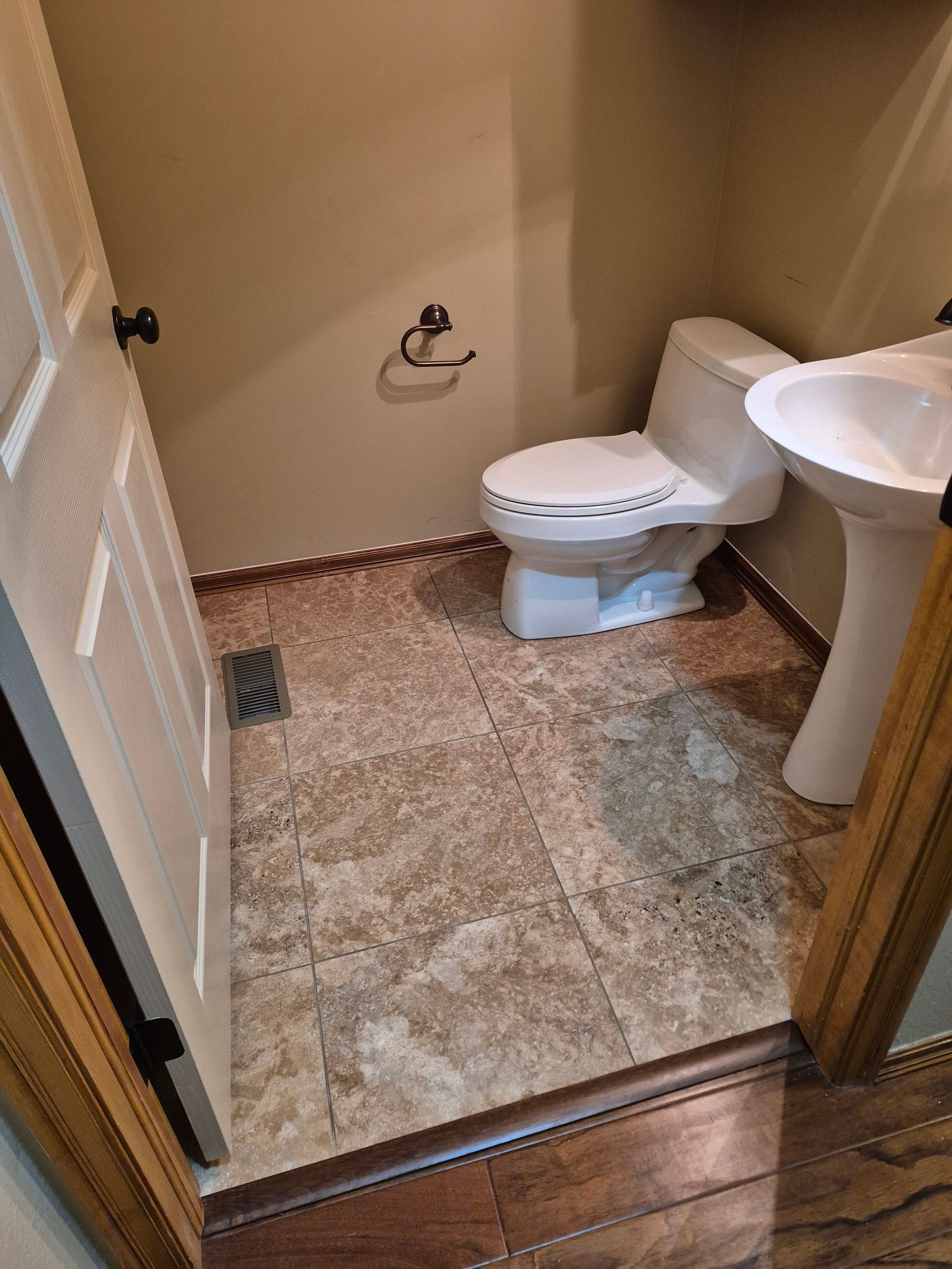 Small powder room with a toilet, sink, and tiled floor.