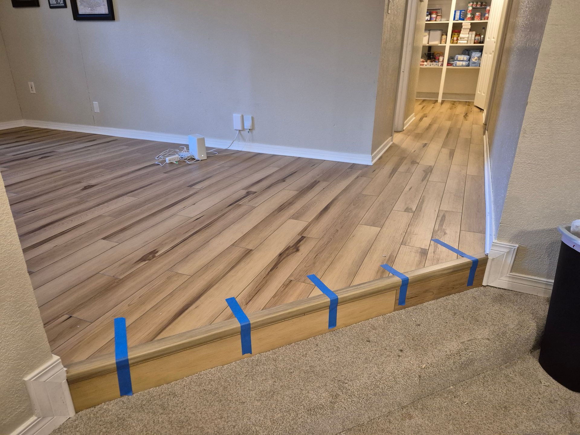 Hardwood floor installation in a doorway, leading from carpeted floor to the new wood flooring.