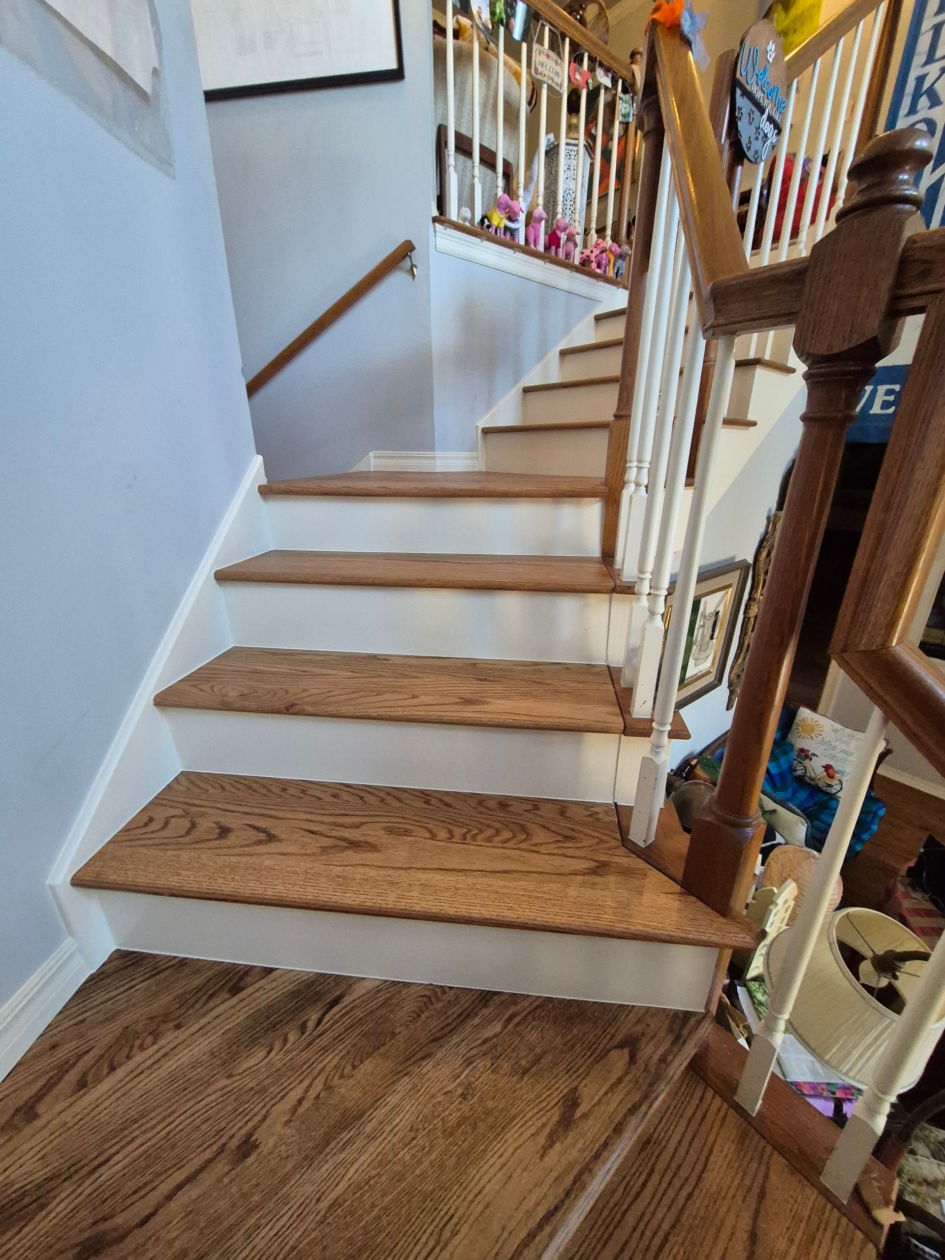 Wooden staircase with white risers, leading upwards. Banister on right, light blue wall on left.