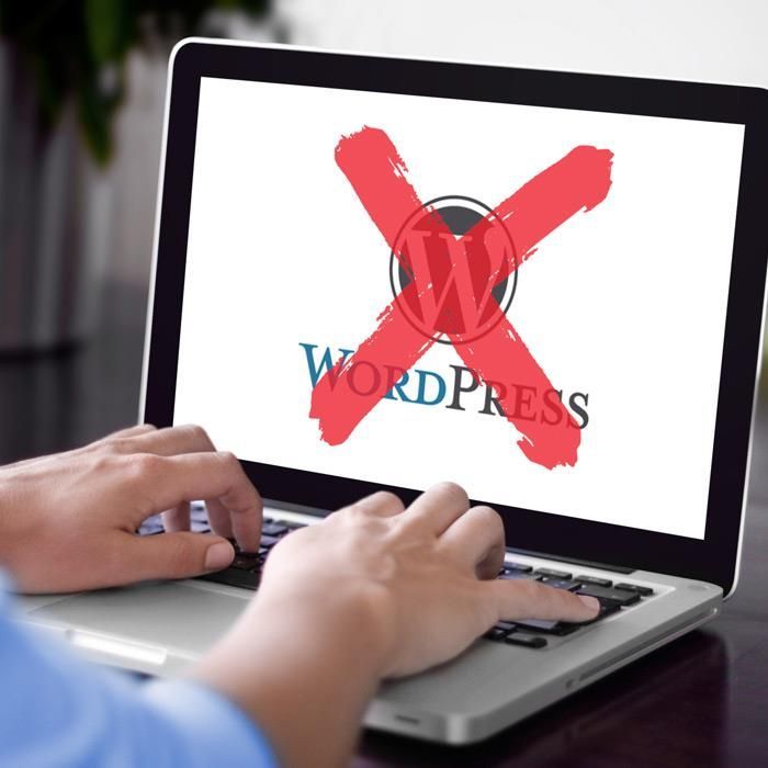 A person is typing on a laptop with the word wordpress crossed out