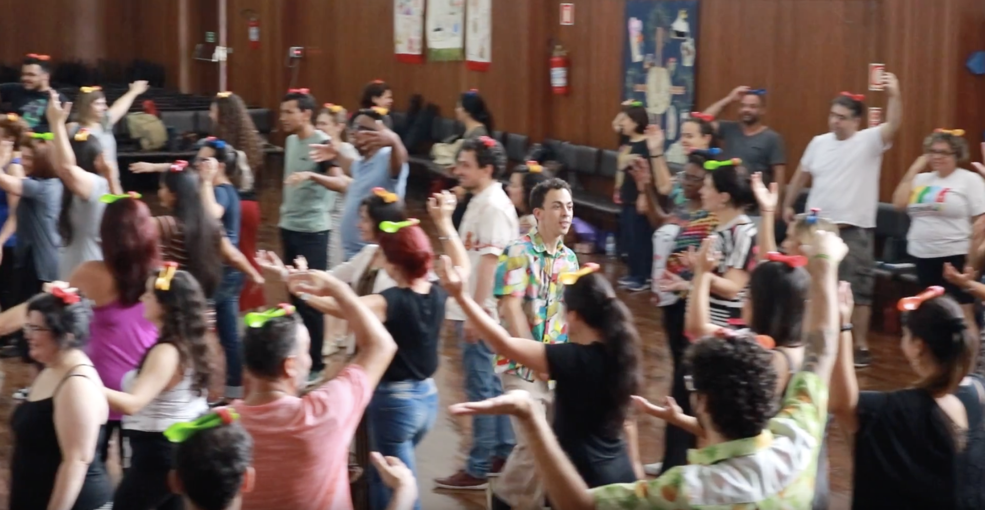 Um grupo de pessoas está dançando em uma sala com os braços para cima.