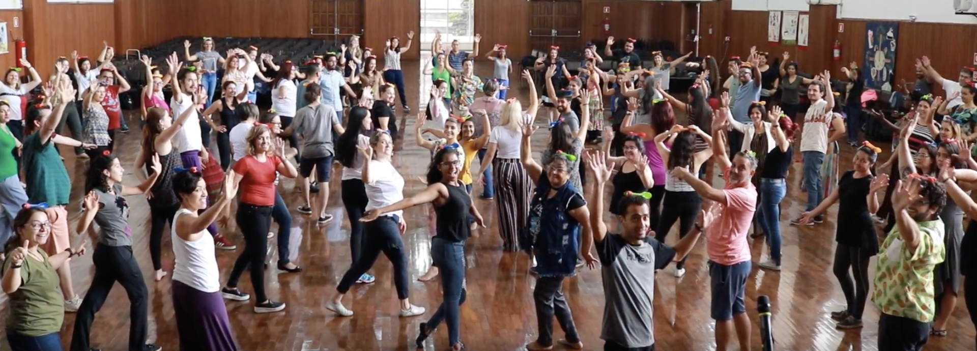 Um grande grupo de pessoas está dançando em uma sala.
